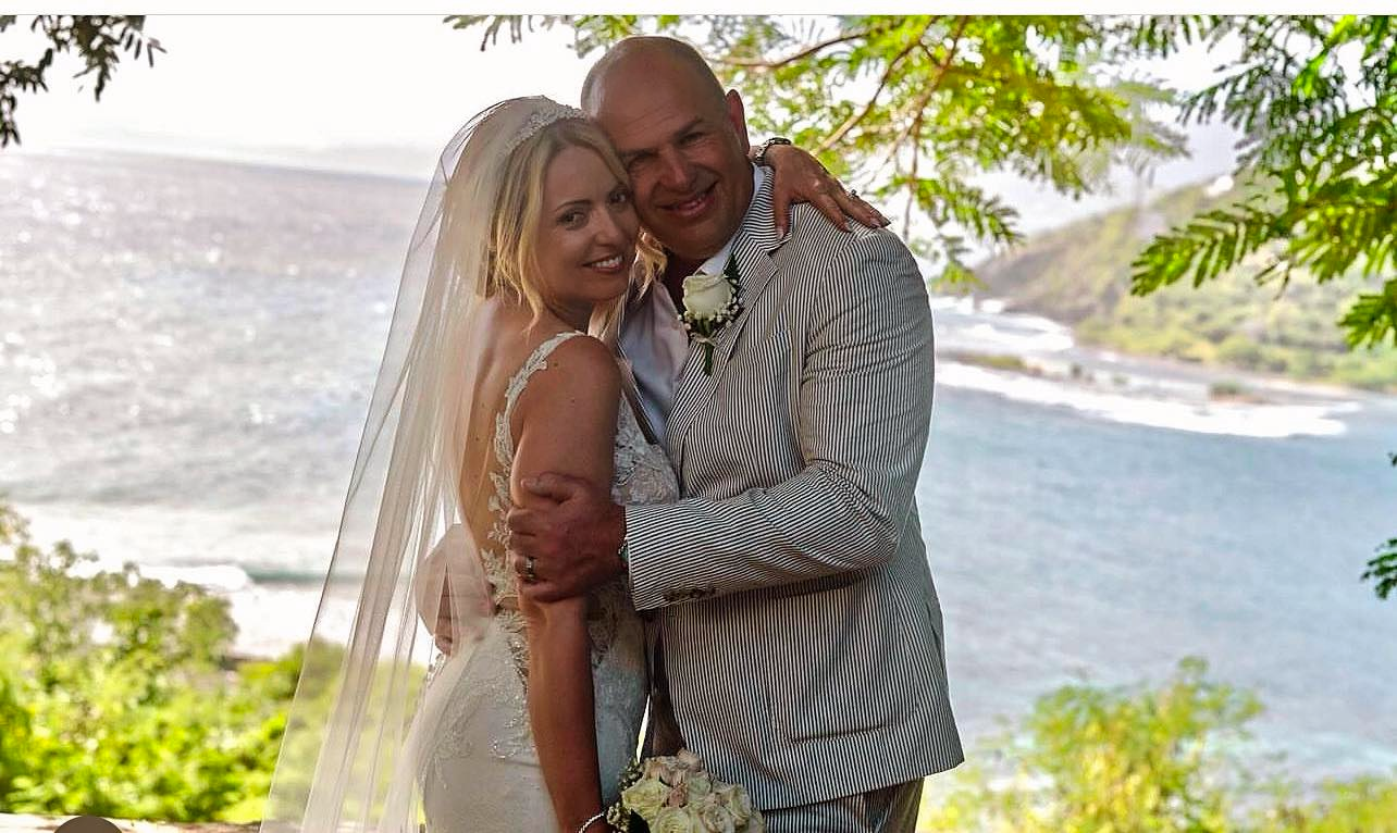 a bride and groom pose for a photo in front of the ocean